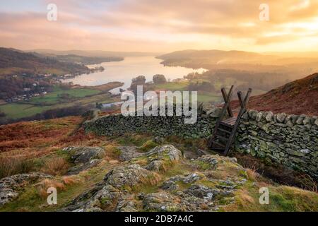Magnifique coucher de soleil sur Windermere dans le Lake District avec un mur en pierre et une pierre au premier plan. Banque D'Images