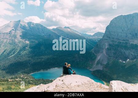 Couple assis sur la falaise, parc national de Glacier, Montana, États-Unis Banque D'Images