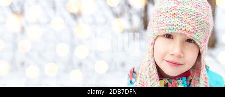 Gros plan portrait d'une belle fille caucasienne 6-7 ans dans un bonnet tricoté d'hiver avec rabats, regardez l'appareil photo. Vacances de Noël et du nouvel an. Banque D'Images