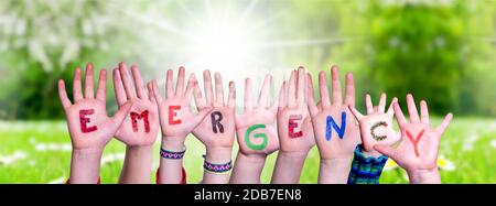 Les mains des enfants Bâtiment de mot coloré urgence. Vert prairie ensoleillé comme arrière-plan Banque D'Images