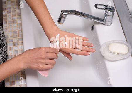 La fille a appliqué la crème à la peau de ses mains sous la forme d'un émoticône Banque D'Images