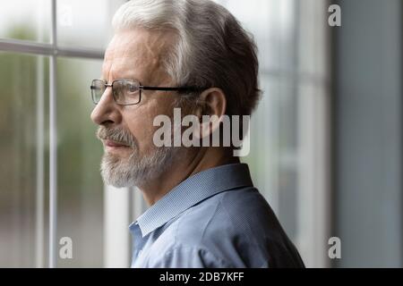 Gros plan sérieux contrarié homme mûr regardant par la fenêtre Banque D'Images