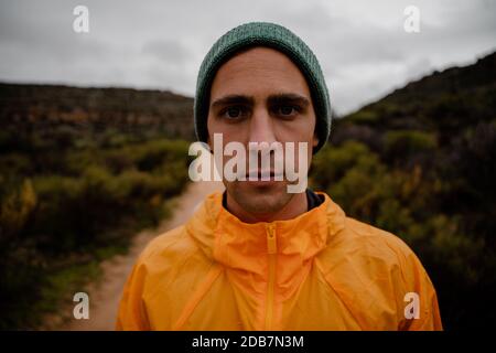 Portrait de la concentration de la forme jeune athlète masculin se reposant après dur piste de montagne sur route de gravier Banque D'Images