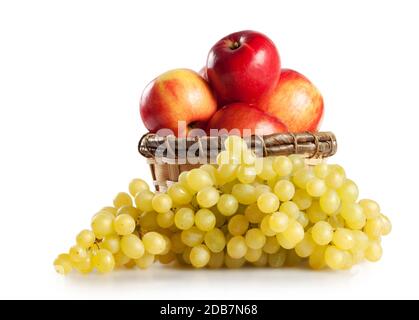 Raisins et pommes dans un panier isolé sur fond blanc Banque D'Images