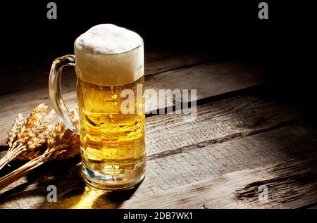 Verre de bière légère avec des épillets sur table en bois Banque D'Images