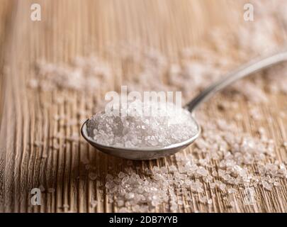 Granuler le sel de mer dans la cuillère sur fond de bois Banque D'Images