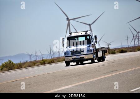 Camion roulant sur l'autoroute à travers les éoliennes près de Mojave in Haut désert de Californie dans la chaleur estivale de l'autoroute 395 Banque D'Images