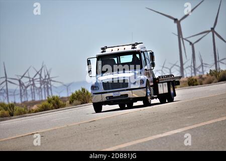 Camion roulant sur l'autoroute à travers les éoliennes près de Mojave in Haut désert de Californie dans la chaleur estivale de l'autoroute 395 Banque D'Images