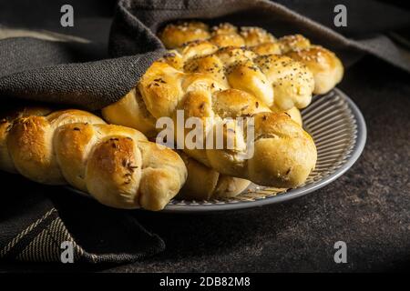 Délicieux petits pains tressés sur une table de cuisine noire. Banque D'Images