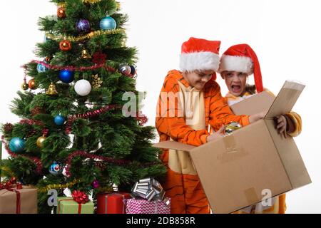 La fille drôle tient une boîte avec les jouets du nouvel an, une autre fille plonge dans une boîte Banque D'Images