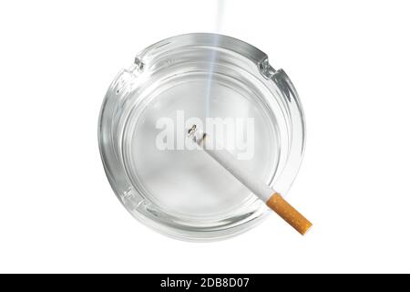 Vue de dessus d'une cigarette allumée dans le cendrier en verre sur blanc Banque D'Images