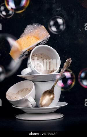 Lavage des tasses à café avec un linge de toilette avec mousse, photo conceptuelle avec des bulles de savon Banque D'Images