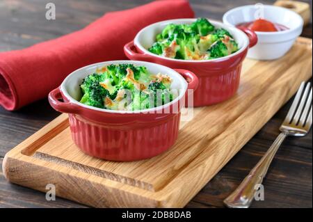 Deux pots de brocoli cuit au four et fromage sur planche en bois Banque D'Images