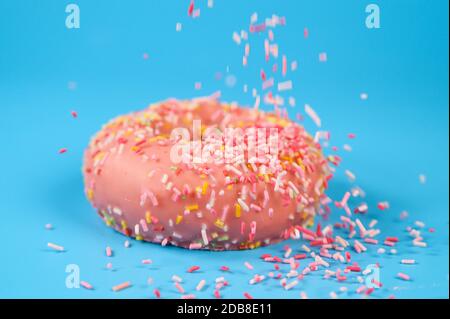 Arroseurs tombant du dessus sur Un Beignet de fraise rose Savoureux. Délicieux dessert sur fond bleu . Banque D'Images