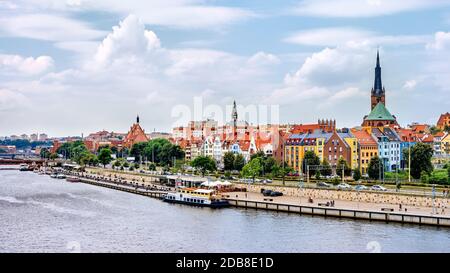 Navires ancrés sur la jetée de la rivière Odra. Les gens se détendant sur le boulevard Piastowski. Cathédrale Basilique St James l'Apôtre en arrière-plan, Szczecin, Pologne Banque D'Images