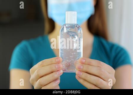 COVID-19 pandémie de coronavirus gros plan femme masque main montrant l'alcool Gel aseptisant distributeur contre 2019-nCoV. Antiseptique, hygiène et santé c Banque D'Images