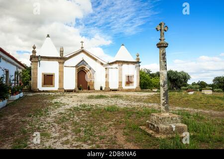 Vue sur le chantier naval du Sanctuaire de Nossa Senhora de Mércoles avec une croix en pierre au premier plan et l'ermitage en arrière-plan. Banque D'Images