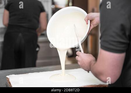 Verser la crème pâtissière chaude. Close up Portrait d'un pâtissier professionnel pour la préparation de desserts au remplissage cuisine étape par étape . Banque D'Images