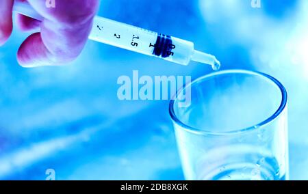 un chercheur vide le liquide d'un flacon dans un contenant en verre pour trouver un vaccin contre le virus dans un laboratoire d'analyse et de recherche scientifique. Science a Banque D'Images