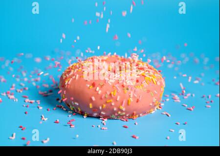 Arroseurs tombant du dessus sur Un Beignet de fraise rose Savoureux. Délicieux dessert sur fond bleu . Banque D'Images