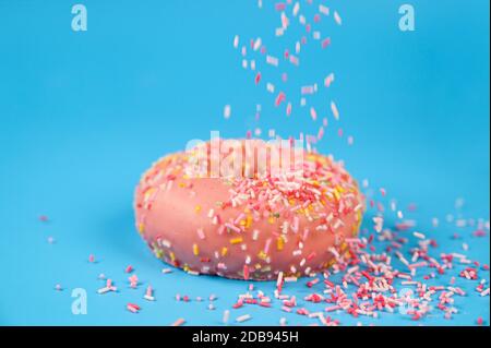 Arroseurs tombant du dessus sur Un Beignet de fraise rose Savoureux. Délicieux dessert sur fond bleu . Banque D'Images