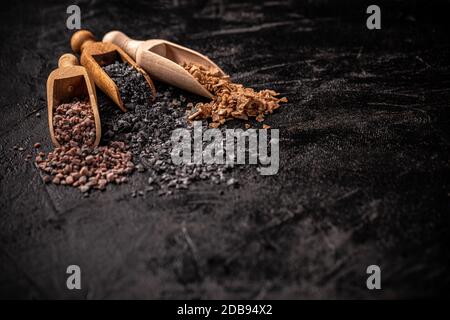 Assortiment de sels gastronomiques en pelle avec espace de copie sur fond noir Banque D'Images