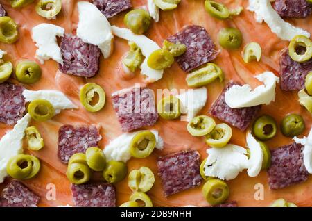 Maison a fait de la pizza crue avec salami, mozzarella, olives et fromage. Vue de dessus. Gros plan Banque D'Images