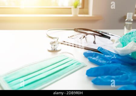 Kit de protection des médecins et des infirmières sur une table blanche avec fenêtre ensoleillée Banque D'Images