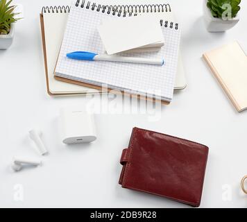 carnets, stylo, pile de cartes de visite, portefeuille en cuir marron et banque d'alimentation avec cordon sur une table blanche, lieu de travail, vue de dessus Banque D'Images