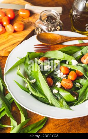 Salade fraîche avec ail sauvage, tomates et feta sur la plaque. Ramsons quitte. Banque D'Images