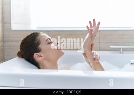 Femme de peau propre dans la salle de bains avec la mousse blanche de cosmétologie Banque D'Images