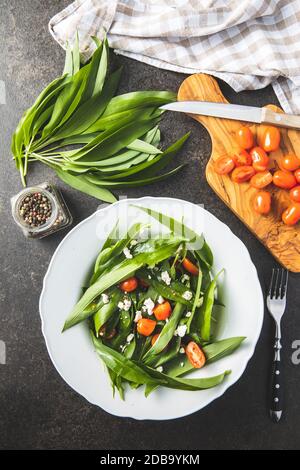 Salade fraîche avec ail sauvage, tomates et feta sur la plaque. Ramsons quitte. Vue de dessus. Banque D'Images