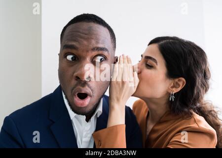 Portrait Of Happy Woman Whispering secrets ou de potins intéressants bel homme dans son oreille Banque D'Images