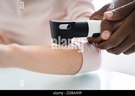 Médecin de la femme examinant la peau du patient de la femme avec le Dermatoscope en clinique Banque D'Images