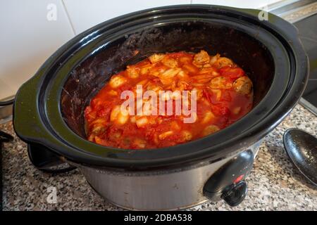 plat de cuisson lent de saucisse, oignon et tomate bouillant sur le plan de travail de cuisine Banque D'Images