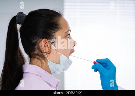 Médecin prenant un échantillon de liquide de bouche de la gorge Banque D'Images