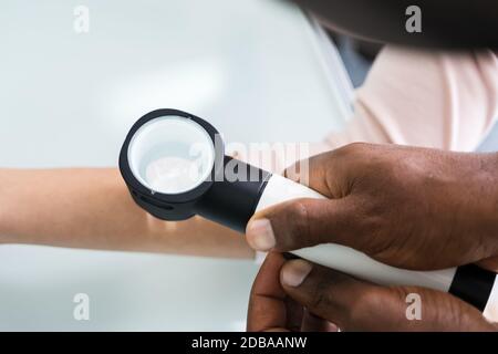 Médecin de la femme examinant la peau du patient de la femme avec le Dermatoscope en clinique Banque D'Images