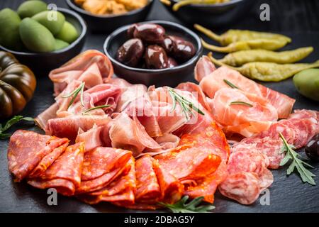 Plateau d'antipastis avec un mélange de salami, prosciutto, chorizo, poivrons, tomates et olives Banque D'Images