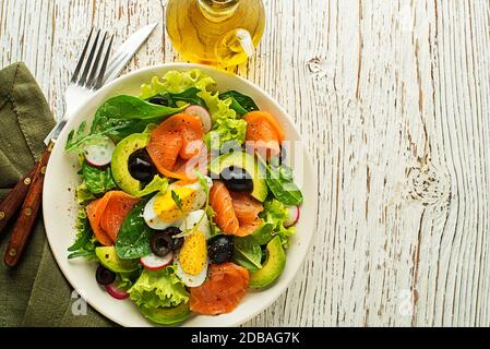 Salade de laitue verte fraîche avec saumon fumé et avocat sur fond de bois Banque D'Images