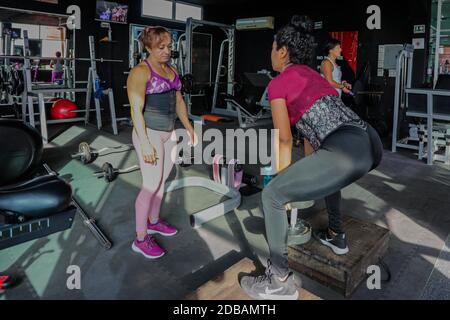 CANCUN, MEXIQUE - NOVEMBRE 16: Entraîneur de fitness Margarita Lopez, soutenir une femme à s'entraîner dans un gymnase dans le cadre de la nouvelle pandémie Covid-19. Margarita a été consacrée pendant deux ans à la formation de personnes dans un gymnase pour soutenir ses trois enfants, l'un d'entre eux avec l'autisme, après que son mari est mort en raison du crime qui a été généré à Cancun; Elle a dû quitter son travail en tant que femme au foyer pour se consacrer à la condition physique et faire face à la crise du coronavirus maintenant sa famille avec ses bénéfices comme entraîneur de fitness. Le 16 novembre 2020 à Cancun, Mexique (photo par Eyepix Group/Pacific Press) Banque D'Images