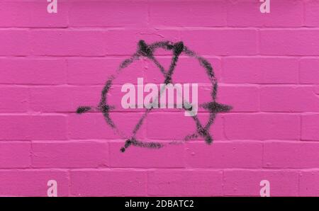 Entourez UN symbole d'anarchie et d'anarchisme peint dessus mur en brique rose Banque D'Images