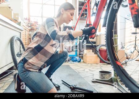 Une femme heureuse travaillant comme mécanicien de vélo pour l'entretien d'un vélo Banque D'Images