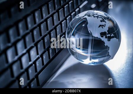 Globe en verre et clavier d'ordinateur sur fond gris Banque D'Images