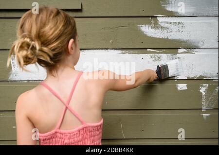 Fille (6-7) peinture mur de chalet Banque D'Images