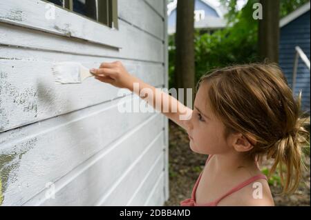 Fille (6-7) peinture mur de chalet Banque D'Images