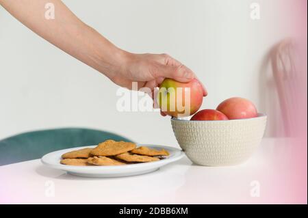 Gros plan de la main de la femme prenant la pomme du bol Banque D'Images