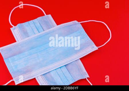 Masques médicaux sous forme de croix médicale sur fond rouge. Symbole masque de protection contre le coronavirus. Masque médical sauve des virus et Banque D'Images