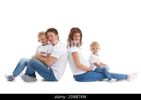 Famille sympathique. La jeune femme enceinte et son mari sont assis avec le dos les uns aux autres avec des enfants, isolés sur un fond blanc. Bon paren Banque D'Images