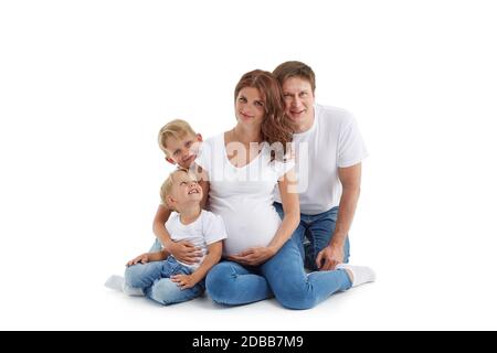 Famille sympathique. Une jeune femme enceinte avec deux enfants et son mari sont assis, isolés sur un fond blanc. Parents heureux. Mère enceinte a Banque D'Images