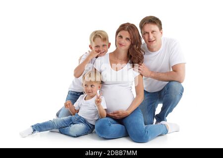 Famille sympathique. Une jeune femme enceinte avec deux enfants et son mari sont assis, isolés sur un fond blanc. Parents heureux. Mère enceinte a Banque D'Images